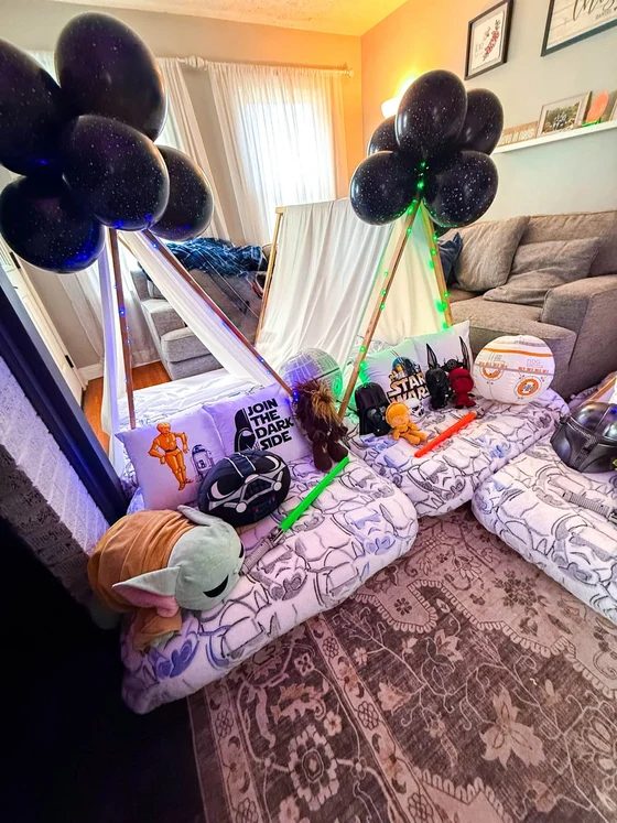 Camp Far, Far Away sleepover setup: Galaxy balloons and glowing lights down the row of tents.