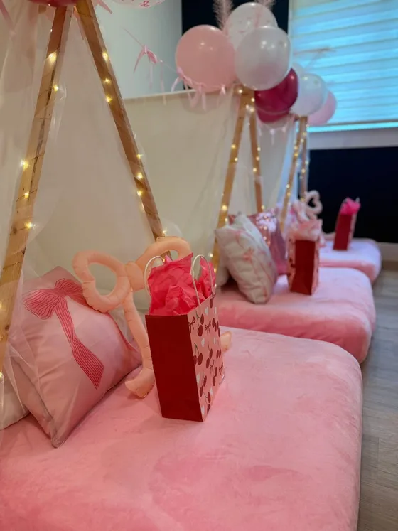 Close-up of a pink bow themed bed with cherry pillows and a gift box