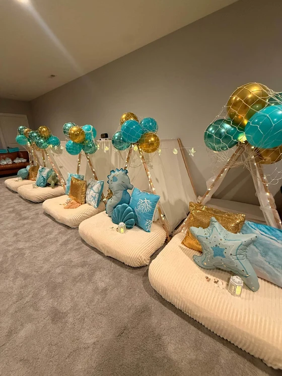 Seaside Dreams sleepover setup: Netted balloons, seashells and sea-blue pillows down the row.