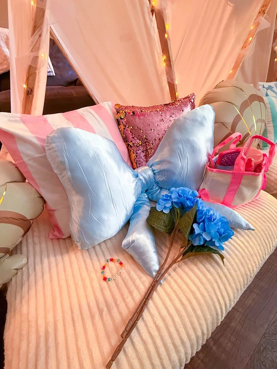 The Summer I Turned Pretty sleepover setup: A satin bow pillow, sequins and hydrangeas.